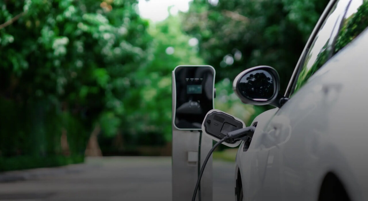 Weißes Elektrofahrzeug, das an eine Ladestation angeschlossen ist.